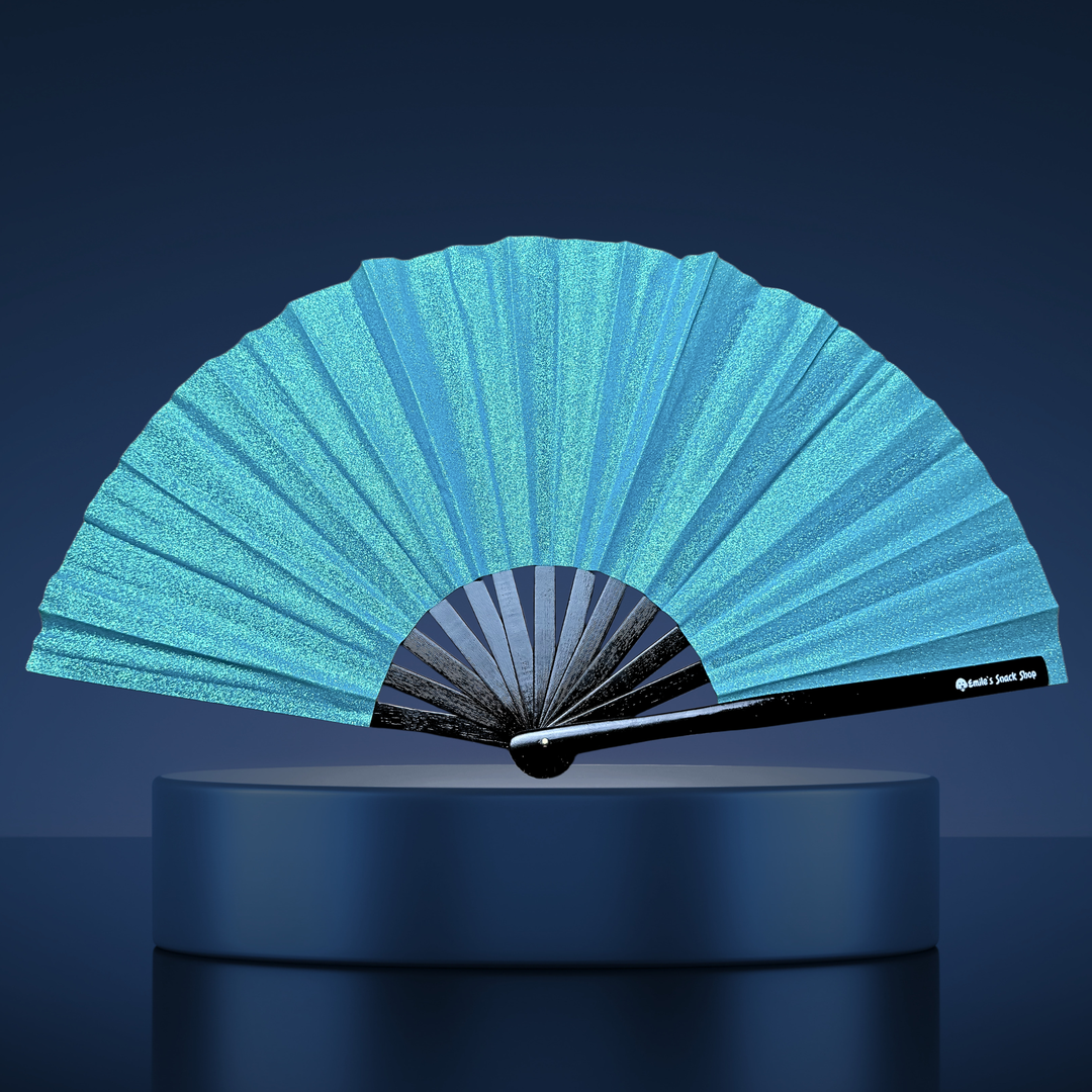 A turquoise blue glitter folding hand fan with a black handle, displayed open on a dark blue pedestal against a dark blue background.
